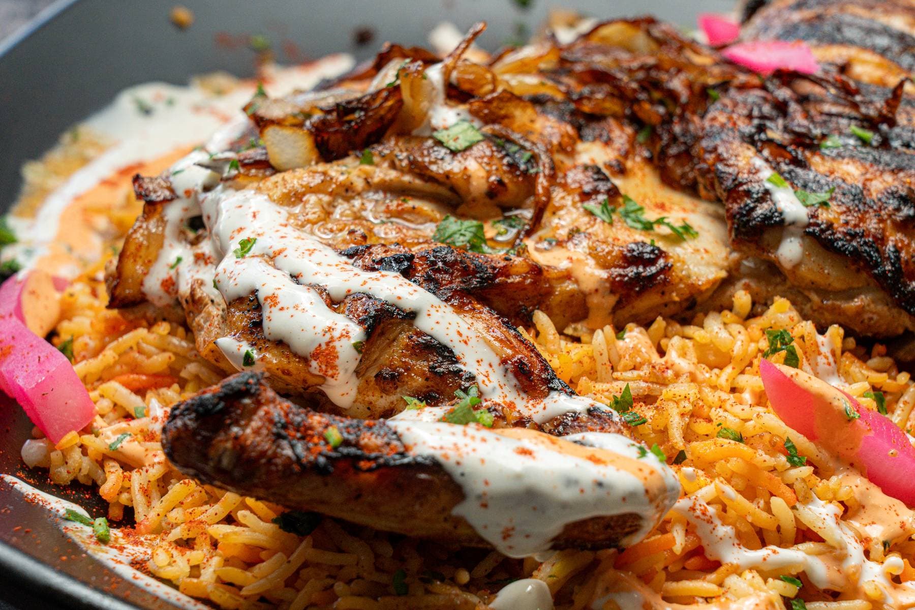 Half chicken, char-grilled and laid over saffron Egyptian rice with white tahini drizzle and pickled turnip